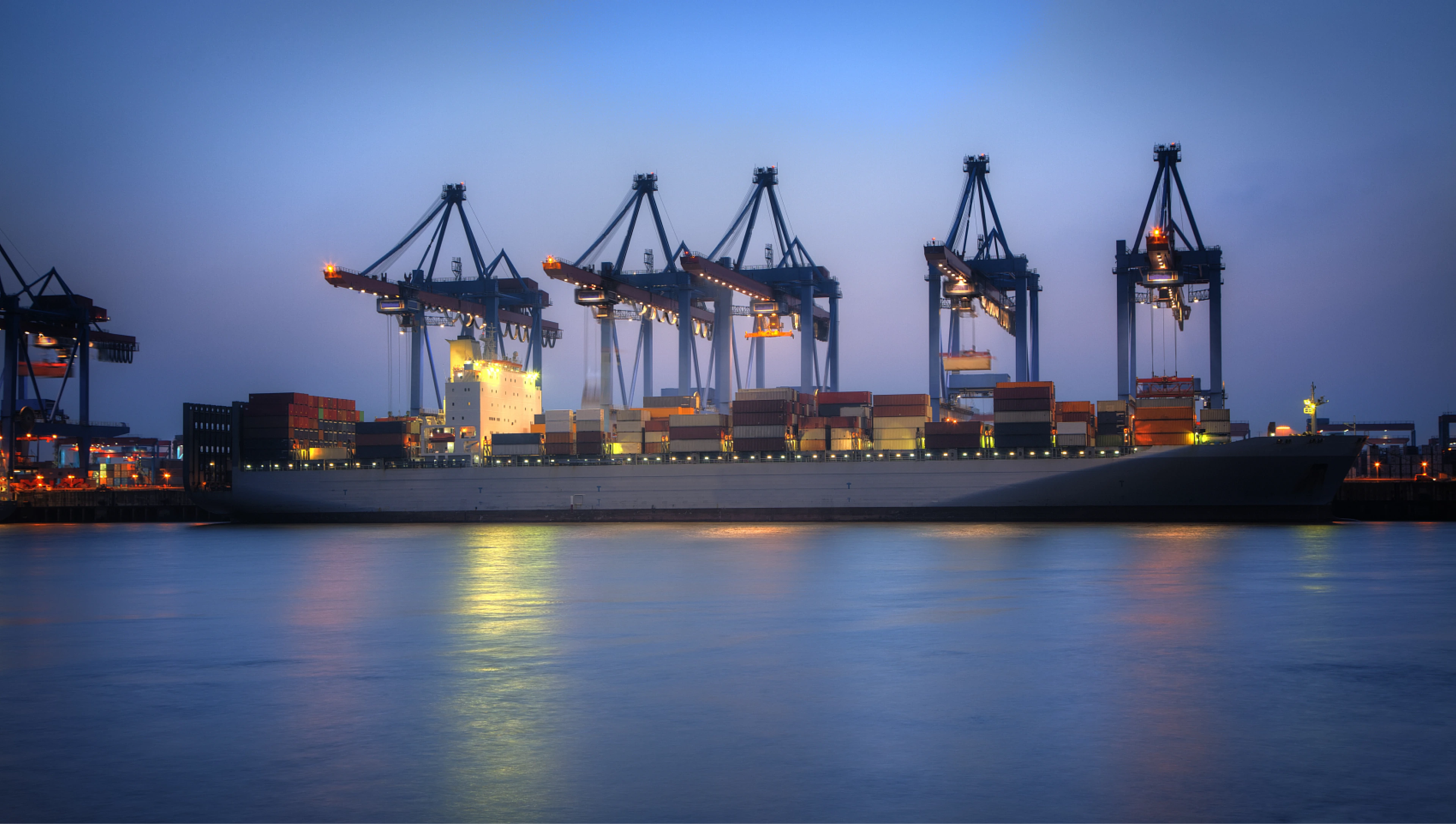 Container ship and cranes illuminated at a port at night